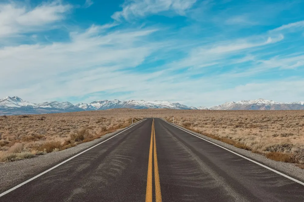 An open highway leading toward distant mountains